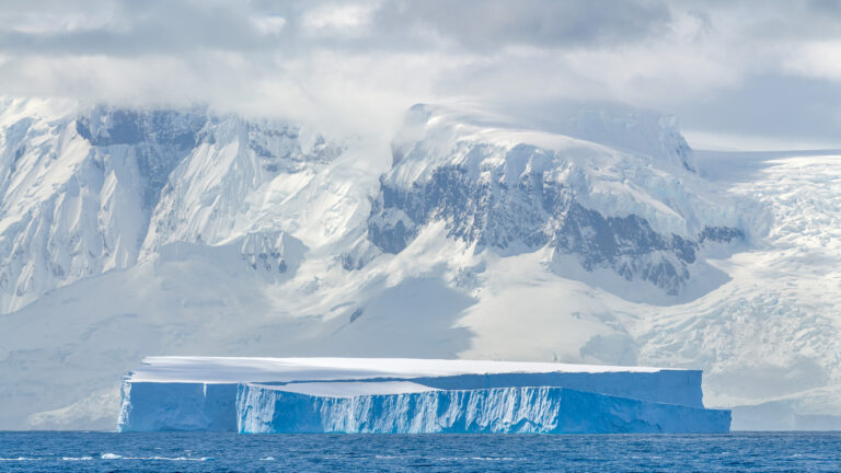 Large tabular iceberg and mountain range in Antarctica