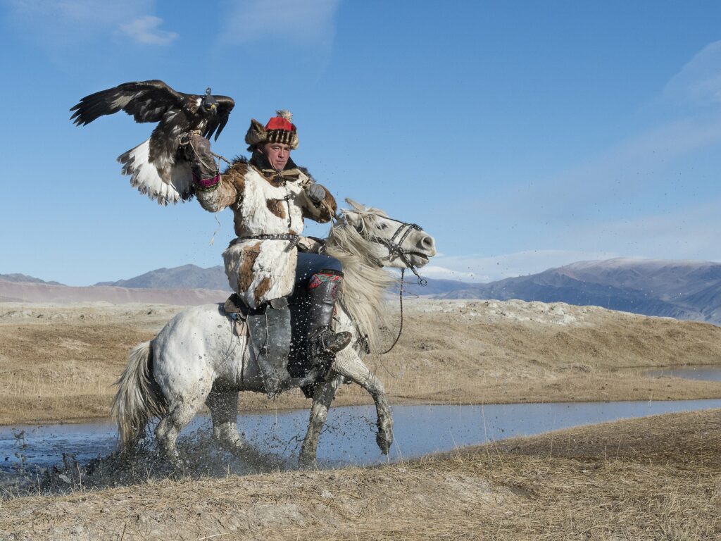Mongolian eagle hunter on horseback holding his golden eagle