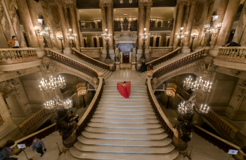 A ballet dancer walks down teh grand staircase at the Palais Garnier