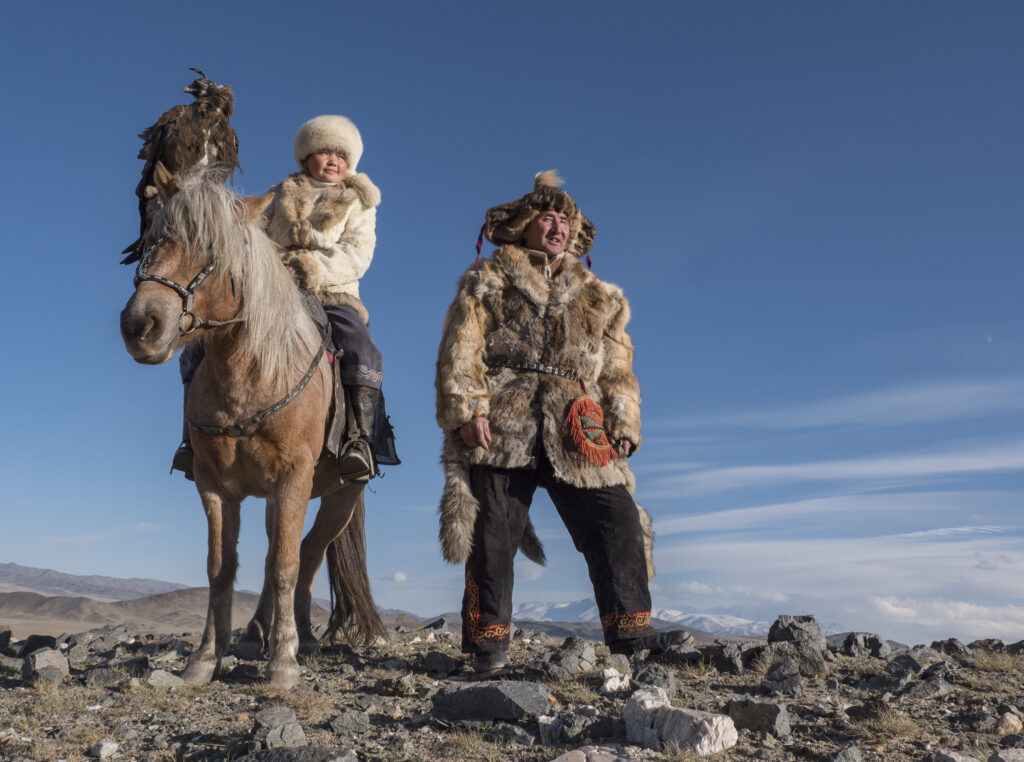 The Eagle Huntress known as Aisholpan stands with her father